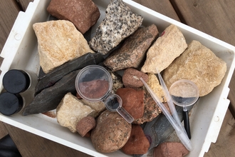 Tray of rocks on picnic table with magnifying glass