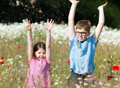 Children waving in meadow Credit Vicky Page / Offshoots Photography
