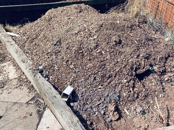 A bug hibernaculum covered with soil - pipes stick out of the soil to allow access and air to the inside of the structure.