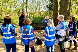 A group of people stand by a river bank for urban river fly training