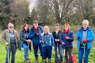 A group of people standing together in a field after planting trees