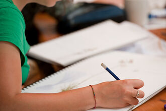 a person wearing a green t-shirt, writing in a sketchbook