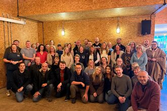 our staff standing in 5 lines as a large group in a room with low lighting - lots of smiling faces