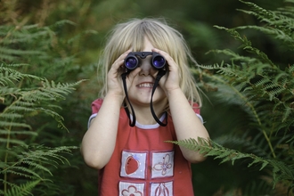 Young girl looking through binoculars. Credit: David Tipling