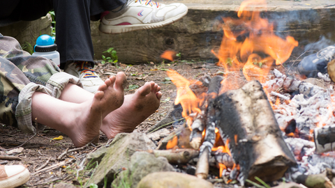 Bare feet warming by a campfire