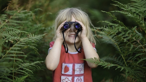 Young girl looking through binoculars. Credit: David Tipling