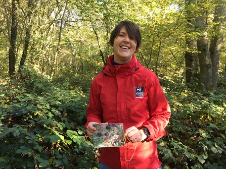 Vicky Dunne in a red coat holding up a photograph of berries