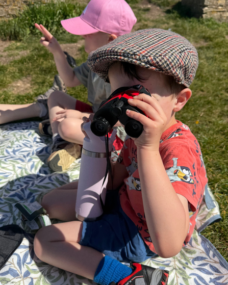 Red binoculars being used by a young boy
