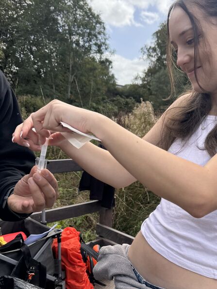 megan is putting the solution into the water taken from a river to test for nitrate and phosphate levels.