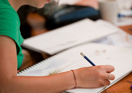 a person wearing a green t-shirt, writing in a sketchbook