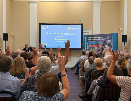 Members with hands in their air, responding to a question from the presenter