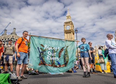 Photo of people stood in front of Big Ben in London at the restore nature now march with a protest banner that says 'protect our rivers'
