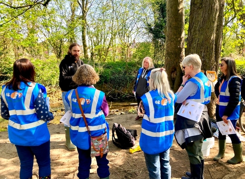 A group of people stand by a river bank for urban river fly training