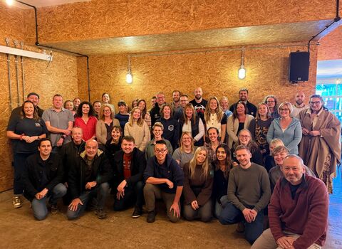 our staff standing in 5 lines as a large group in a room with low lighting - lots of smiling faces